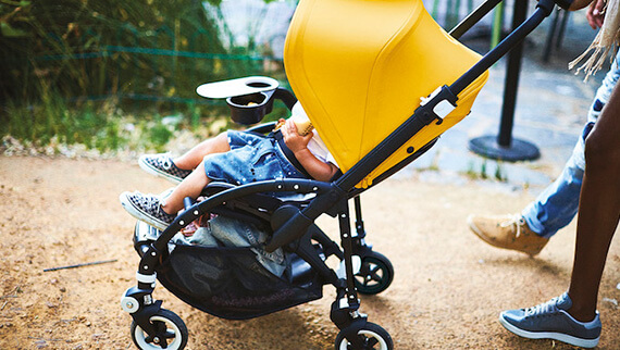 Niño en el cochecito con familia en el jardín.