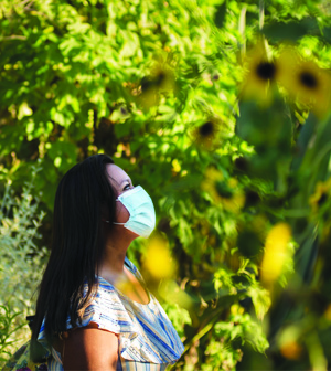 Woman in mask enjoying sunflowers
